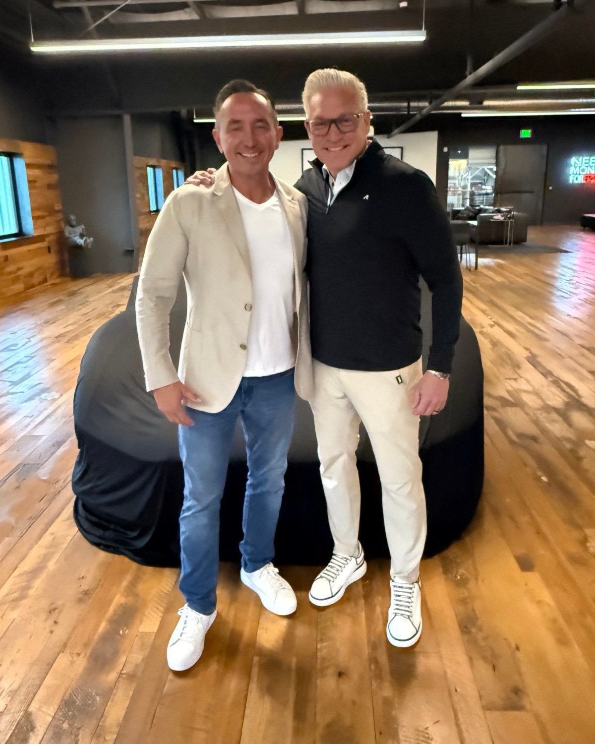 No Limit Garages founders Ed, left, in a tan blazer, and Ryan, right, standing in front of a covered car in the garage