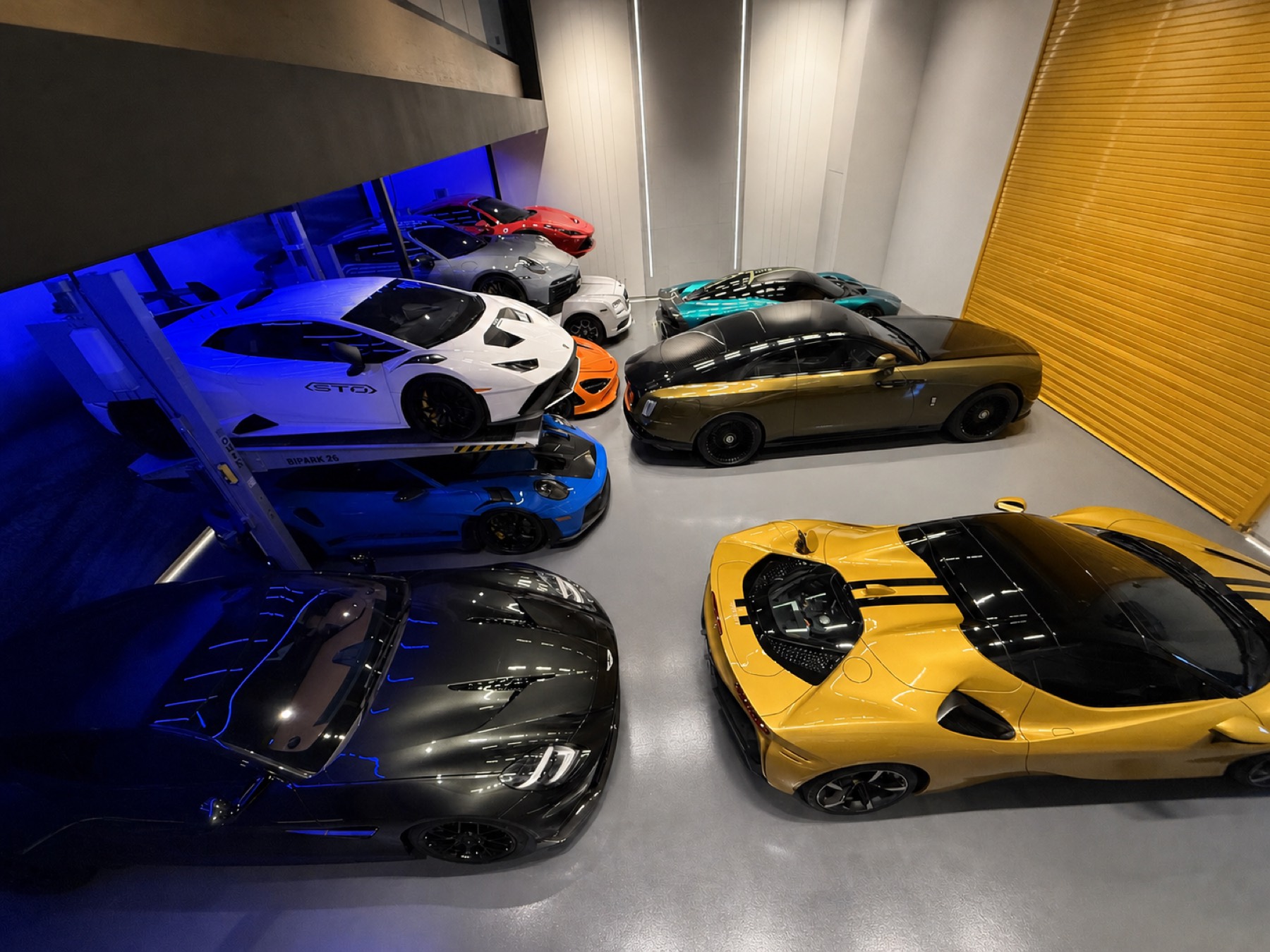 Supercars parked in rows under blue light