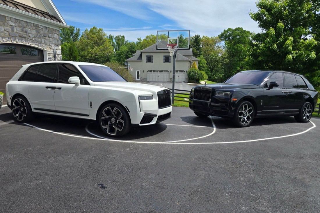 White and black Rolls-Royce Cullinans parked side by side